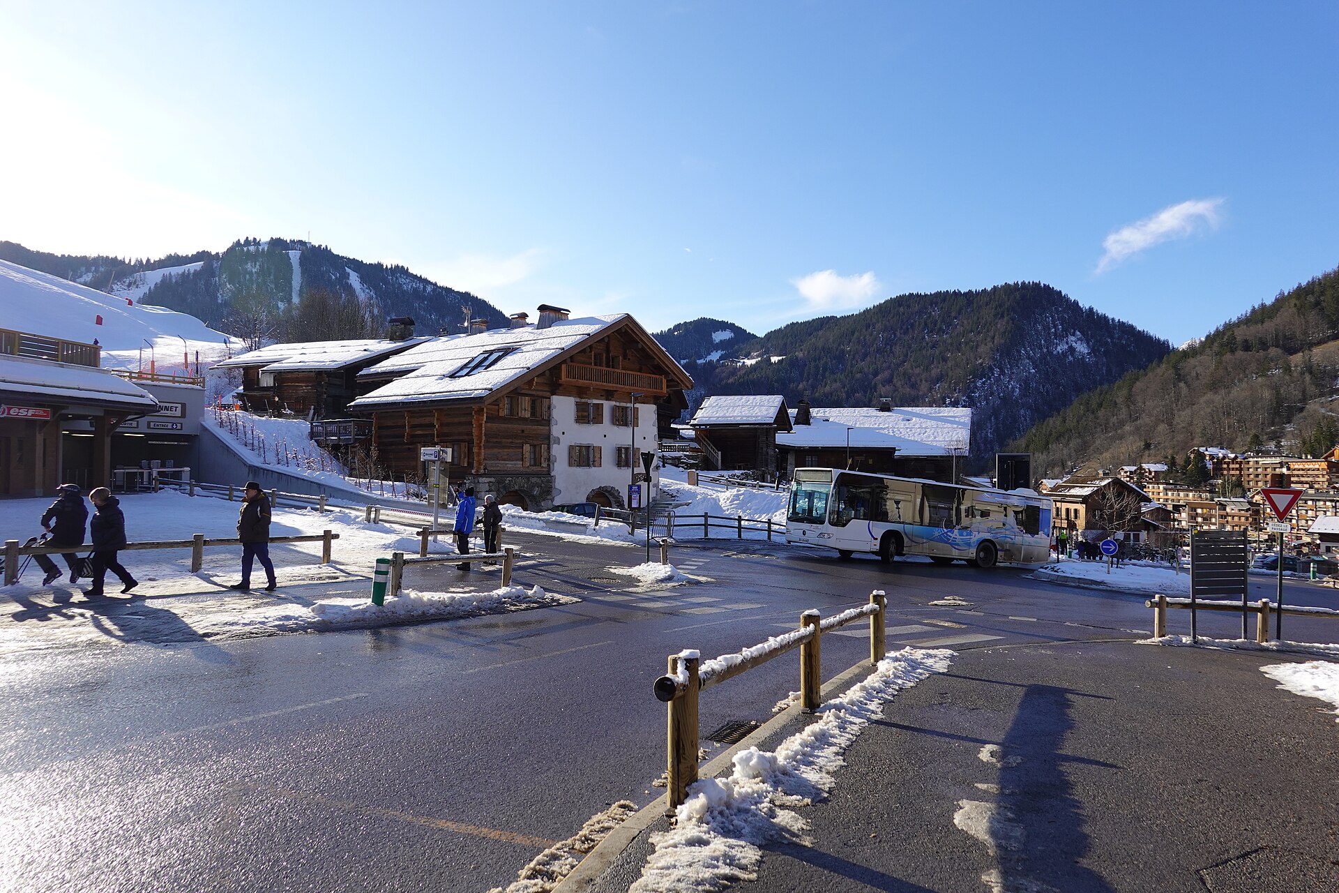 Chalets et rue enneigés du village de La Clusaz, dans les Alpes, avec les montagnes en arrière-plan.